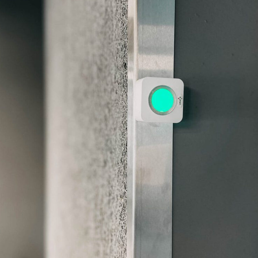 Luxafor Cube Busylight hvid lyser grønt på væg ved kontor